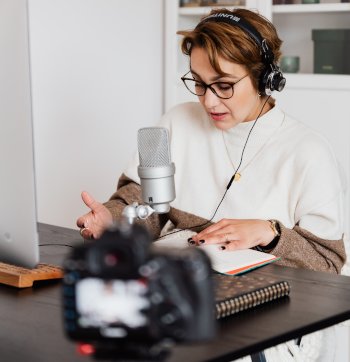 Business woman sitting at desk creating content on camera.