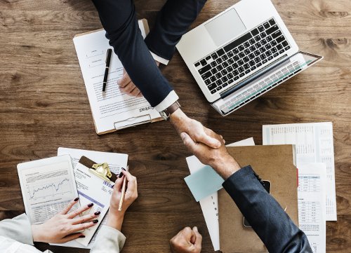 Handshake over a table filled with planning materials