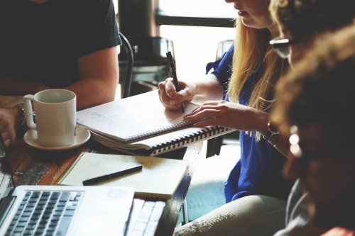 Woman taking notes during a pre-production meeting with several attendees