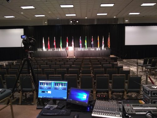 Large event stage with flags, colored lights, screens and video equipment